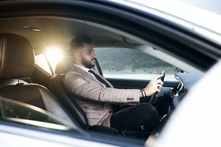 guy in car with laptop and phone