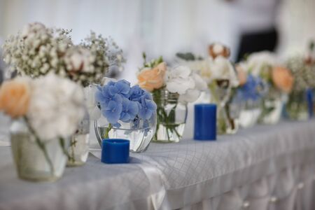 bouquets of various flowers as a decoration on wedding tables in a restaurantの写真素材