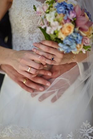 the groom hugs the bride who holds a wedding bouquet in her handsの写真素材