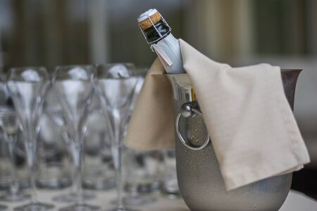 a bottle of champagne in a bucket with ice and glassesの写真素材