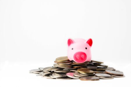 Small pig doll set on pile of coins on isolated white backgroundの写真素材