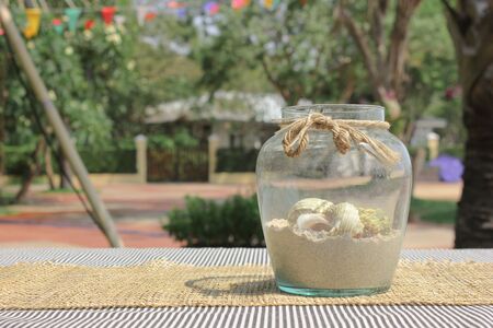 Sea shell in bottle glass decorated on the table in the gardenの写真素材