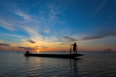 A Silhouette Fisherman Catching Fish from square dip net at Pak Pra Canal in early morning during golden sunrise momentの写真素材