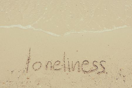 Handwritten Word Loneliness On Sand Of Beach with vintage style,background and texture