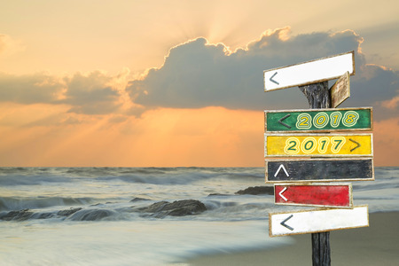 Wooden blank sign with text 2018 and 2017 with sunrise beach background