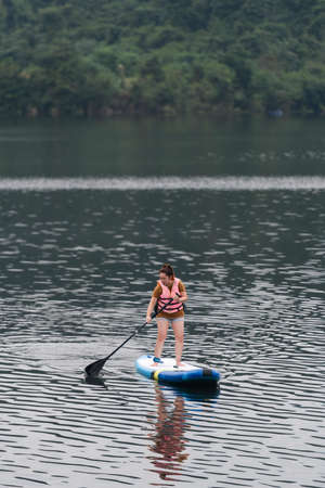 A woman stand up paddle boards (SUP) on a calm Lakeの写真素材