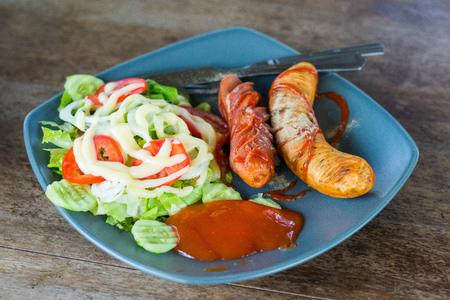Sausage steak in a dish on wooden floorの写真素材