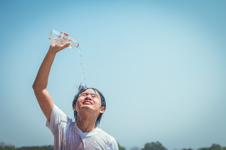 Young man pouring water to cool his head.の写真素材