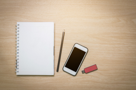 Top view Notebook,smart phone,pencil,flash drive on the desk is a wooden surface with copy spaceの写真素材