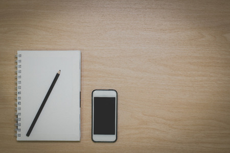 Top view Notebook,smart phone,pencil on the desk is a wooden surface with copy spaceの写真素材