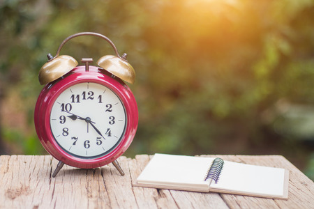 An empty note pad rests on a wooden balcony. With a clock in the morning.の写真素材