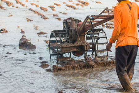 Farmers are adjusting the field's ground using a plowing tractor to prepare the crop.の写真素材