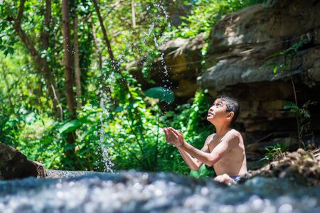 Boy playing waterfall Flowing from the jungleの写真素材