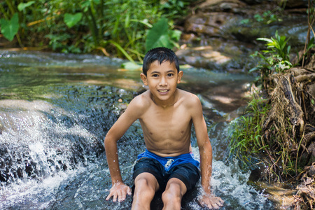 Boy playing waterfall Flowing from the jungleの写真素材