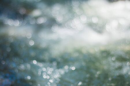 Blurred white bokeh picture of the tide that hits the sun in the daytime.