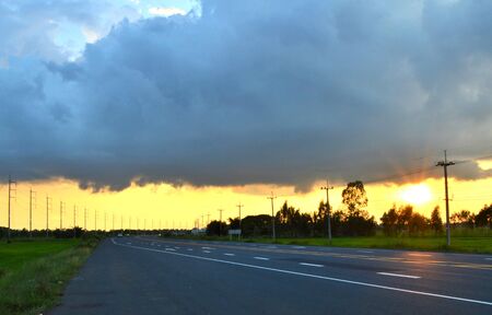 Road scenery in evening include sunset, cloud, cornfield, trees and electricity postの写真素材