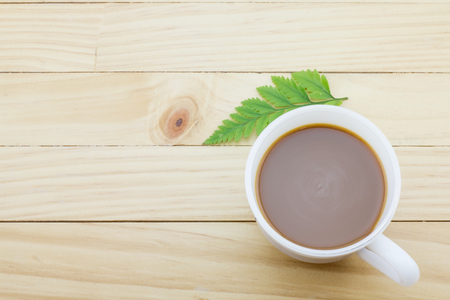 Coffee mug with green foot fern on yellow rustic table.の写真素材