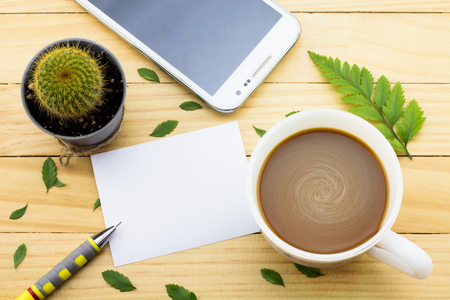 Coffee mug with green foot fern, Flower petals, Cactus flower, Pen, phone calls and notes on yellow rustic table.の写真素材