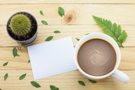 Coffee mug with green foot fern, Flower petals, Cactus flower and notes on yellow rustic table.の写真素材
