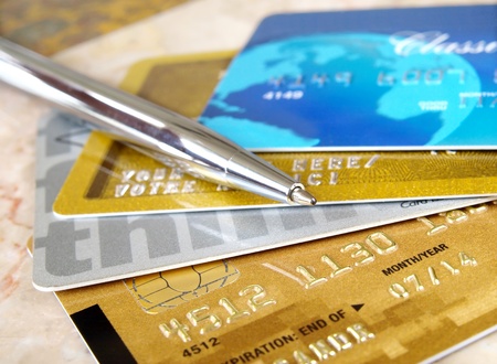 Silver pen on the pile of credit cards .