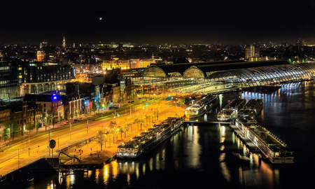 Amsterdam, Netherlands - MAY 10, 2016: River cruise terminal with ships and Centraal Train Station in Amsterdam at nightのeditorial素材
