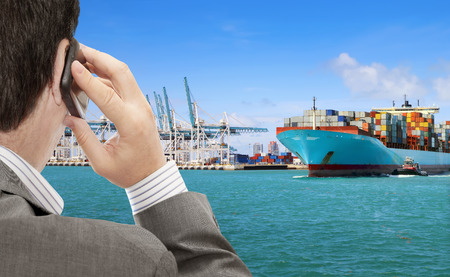 Businessman use smart phone for logistic business, in the background container terminal with cargo shipの写真素材