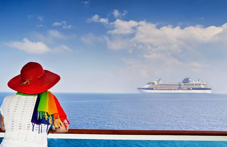 Lady on the ship looking at cruise ship sailing from portの写真素材