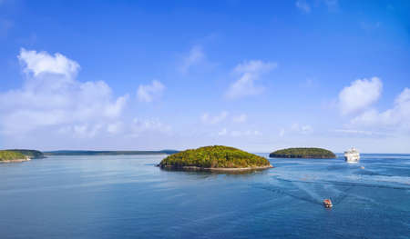 Panoramic view of Bar Harbor with cruise ship, touristic boats and cluster of small islands on a sunny dayの写真素材