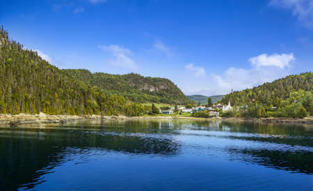 View from harbor in Canadian fjord on small village between mountainsの写真素材