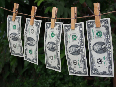 Two dollar bill fixed on clothes peg with green blur backgroungの写真素材