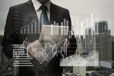 Double exposure of Businessman Using Digital Tablet with the virtual panel of pie chart and other chart , business conceptのeditorial素材