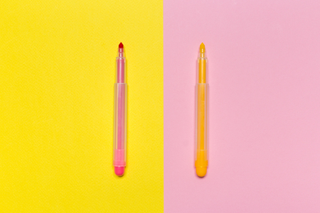 Two pencils lie on two pastel color papers pink and yellow top viewの写真素材