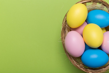 Colorfull easter eggs in nest on green pastel color background with space.の写真素材