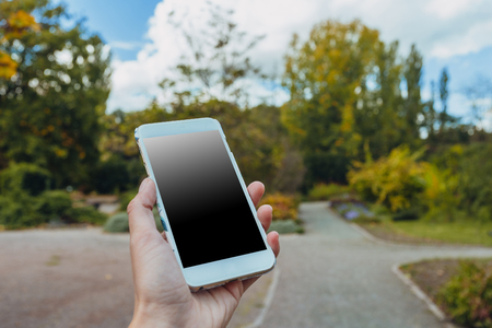 Closeup of female hand using a smart phone in parkの写真素材