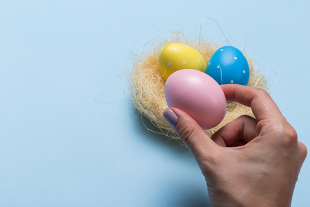 Colorfull easter eggs in nest on blue pastel color background with space.の写真素材
