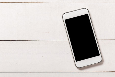 Mobile phone with blank screen on wooden table background. Smartphone on wood old plank vintage texture background. top viewの写真素材