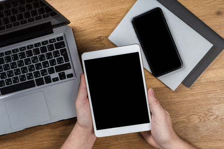 Hand touch on empty screen of tablet above brown table top view, Leave space for display of your content, Technology concept, mock up for montage your contentの写真素材