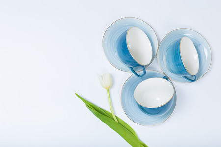 Clean dishes, coffee or tea set. Plenty of elegant porcelain cups and saucers with flower inside at white background, high key, top view and flat lay.の写真素材