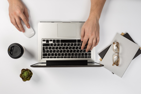 Male hands working on modern laptop. Office desktop on white backgroundの写真素材