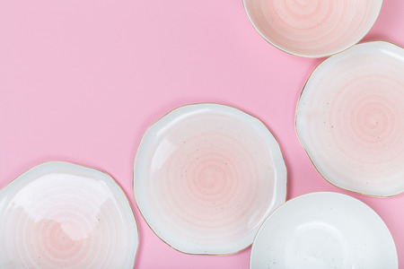 Empty plates and bowls on pink background. Top view with copy spaceの写真素材