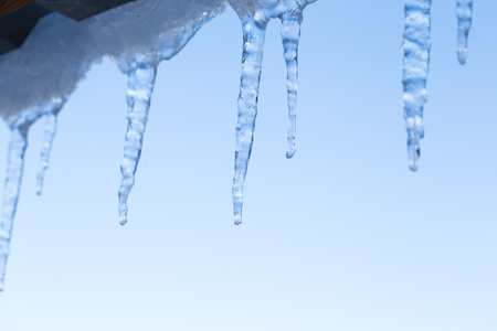 Icicle on the roof of the pipe,Building covered with big icicles,Icicles hang from the roof, vertical, ice stalactite hanging from roofの写真素材