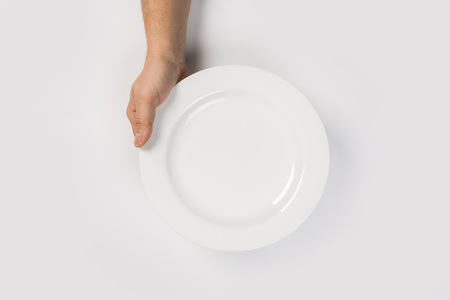 male hands are holding a plate on a white isolated backgroundの写真素材