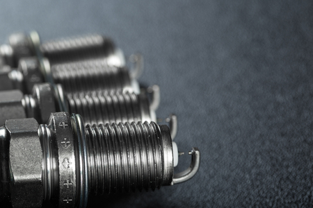 A set of new spark plugs of the car, and spare parts of vehicles on a dark  background. Studio macro image of high quality. To advertise auto service.の写真素材