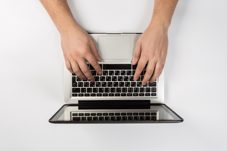 Male hands working on modern laptop. Office desktop on white backgroundの写真素材