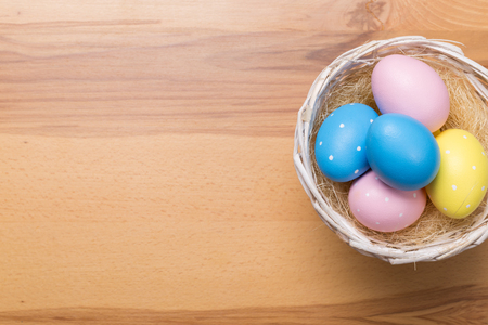 Easter eggs in the basket on wooden backgroundの写真素材