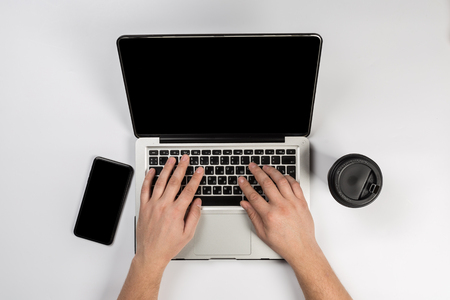 Male hands working on modern laptop. Office desktop on white backgroundの写真素材