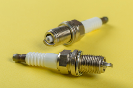 A set of new spark plugs of the car, and spare parts of vehicles on a yellow background.