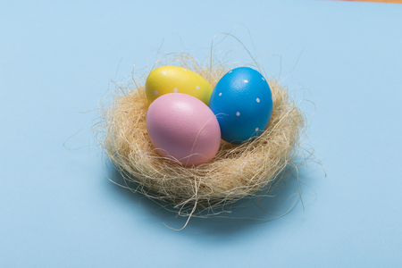 Colorfull easter eggs in nest on blue pastel color background with space.の写真素材