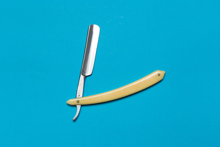 Shaving razor isolated on soft blue background.Straight razor with brown handle.