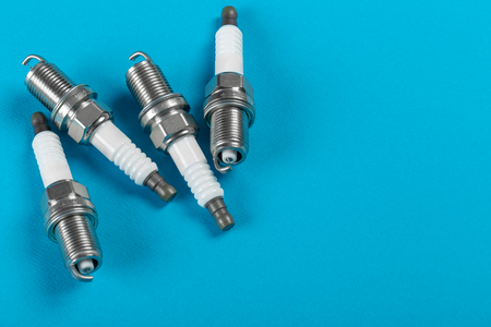 A set of new spark plugs a blue background. Studio macro image of high quality. To advertise auto service.の写真素材
